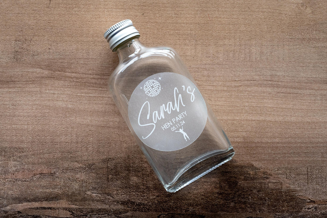 Printed using white ink, the bride-to-be's name is centre in a lovely handwriting font. There is an image of a disco ball and dancing queen at the top and bottom of the sticker to match the party theme of the hen party.