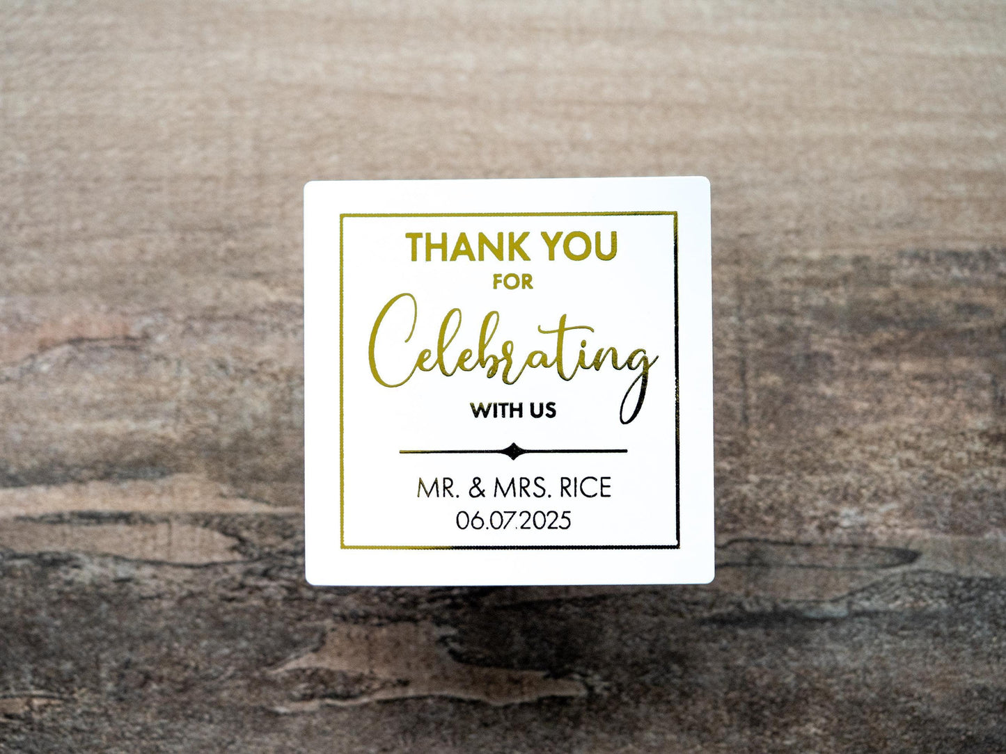 Custom square sticker with "Thank You For Celebrating with Us" written on the middle of the sticker. At the bottom of the sticker is the name of the bride & groom and the date of their special day. The sticker is layered with lovely metallic foil