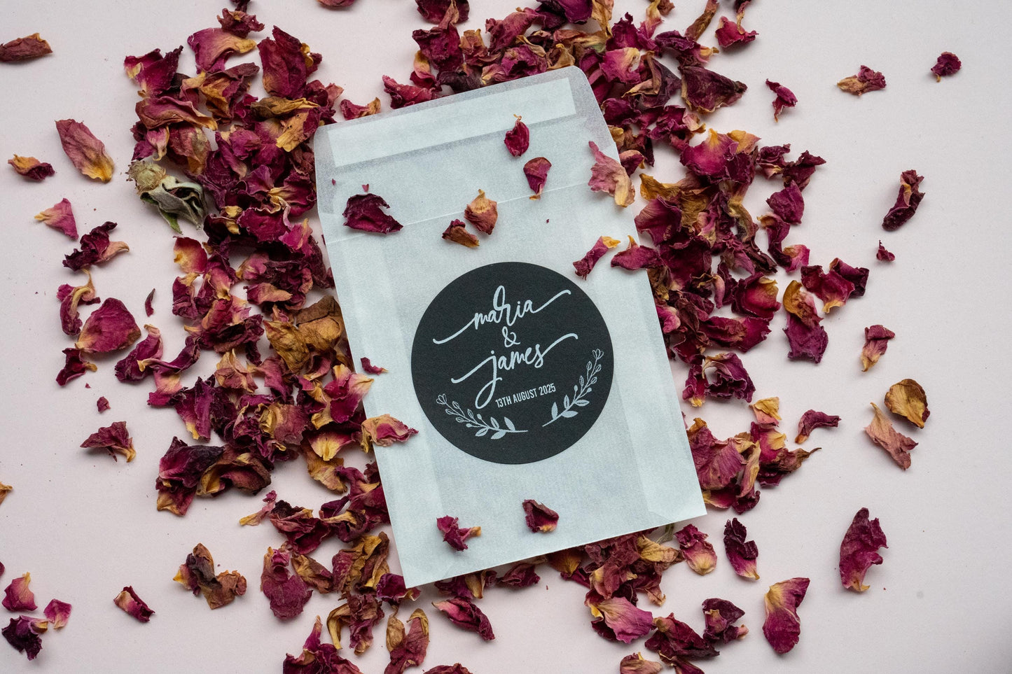 A black sticker with the names of the married couple in a lovely handwritten font in the middle of the sticker. A leaf frame is at the bottom with the date of the wedding day. Printed in white ink so it stands out on the black sticker.