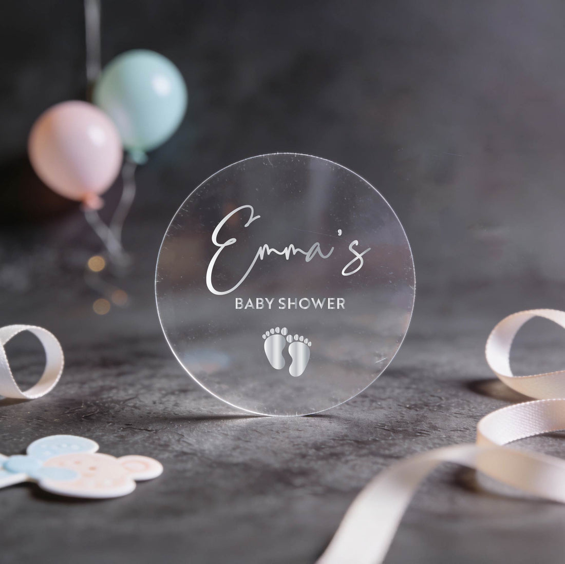 Clear transparent round sticker with 'Emma's Baby Shower' text in gold foil.