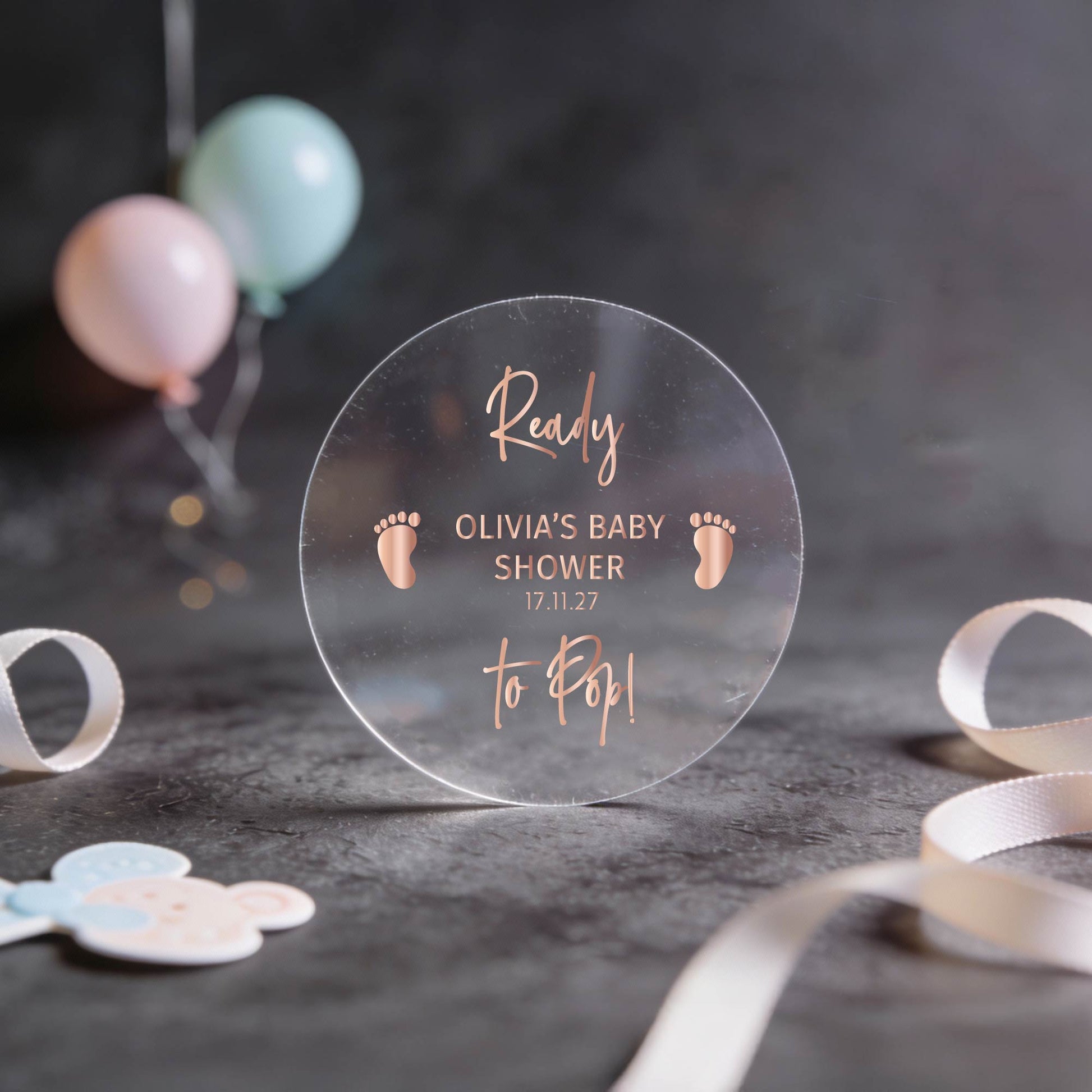 Transparent clear sticker with rose gold text writing saying: "Ready to Pop! Olivia's Baby Shower 17.11.27." 