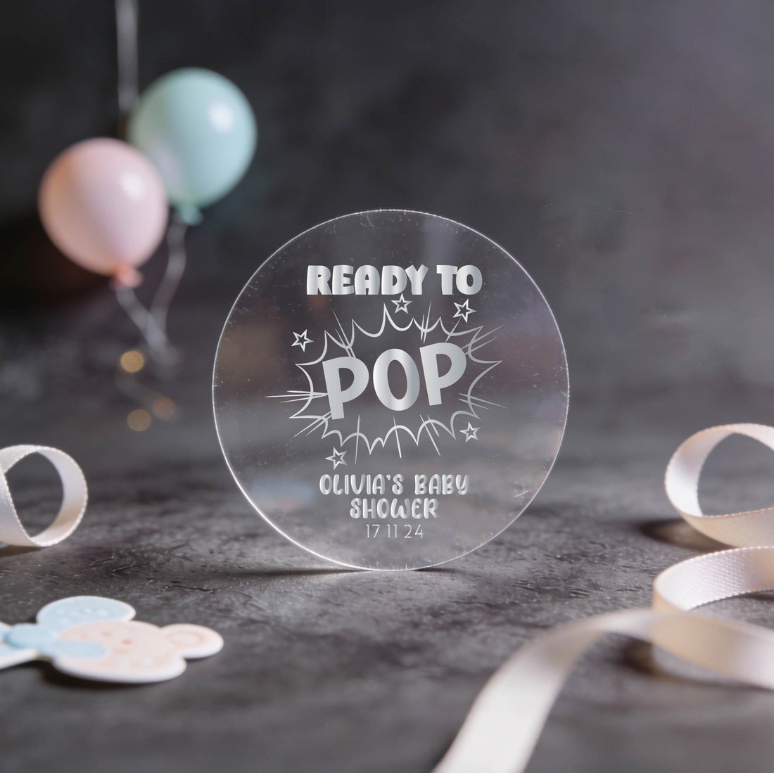 A transparent round sign reads "Ready to Pop" in gold foil letters, surrounded by stars. It announces "Olivia's Baby Shower" with the date "17 11 24."