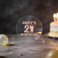 A clear round sticker with rose gold foil text reading 'ANDY'S 21st BEER'TH DAY' and a beer glass icon.