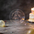 A clear round rose gold foil sticker with an image showing a hand holding a wine glass and the text 'Sip Happens', 'Amanda's 30th Birthday' & 'Thank you for celebrating'. The background is a dark birthday scene with blurred balloons and a lit cake.