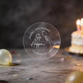 A clear round silver foil sticker with an image showing a hand holding a wine glass and the text 'Sip Happens', 'Amanda's 30th Birthday' & 'Thank you for celebrating'. The background is a dark birthday scene with blurred balloons and a lit cake.