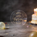 A clear round transparent sticker with gold foil text reading 'AMELIA'S 40th Birthday
