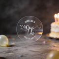 A hand holds a clear round sticker with silver foil text reading 'AMELIA'S 40th Birthday