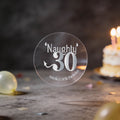 A clear round sticker with silver foil lettering that reads 