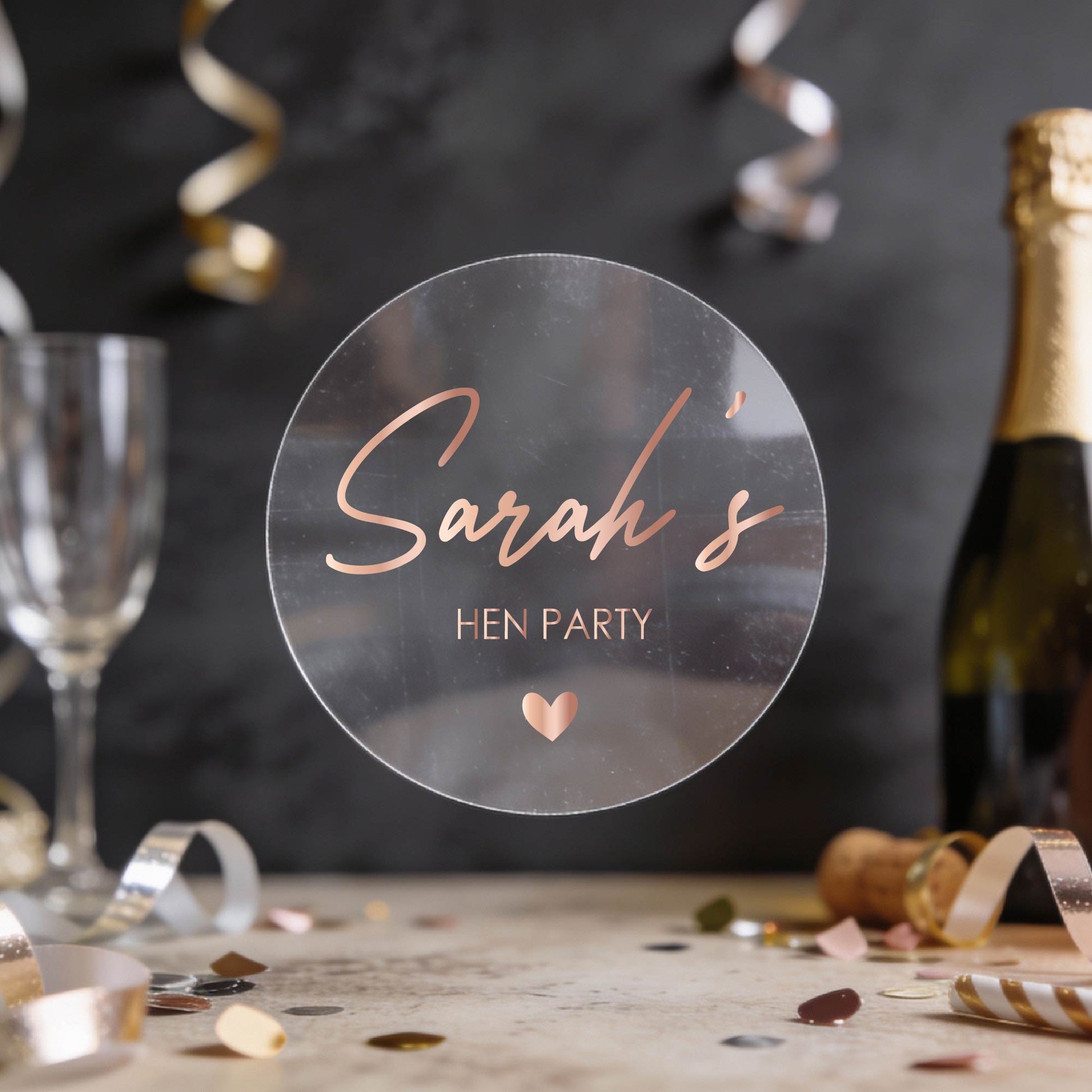 Personalised 'Sarah's Hen Party' round transparent sticker written in rose gold foil. 