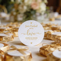 A round, white gloss sticker with gold foil text reads 