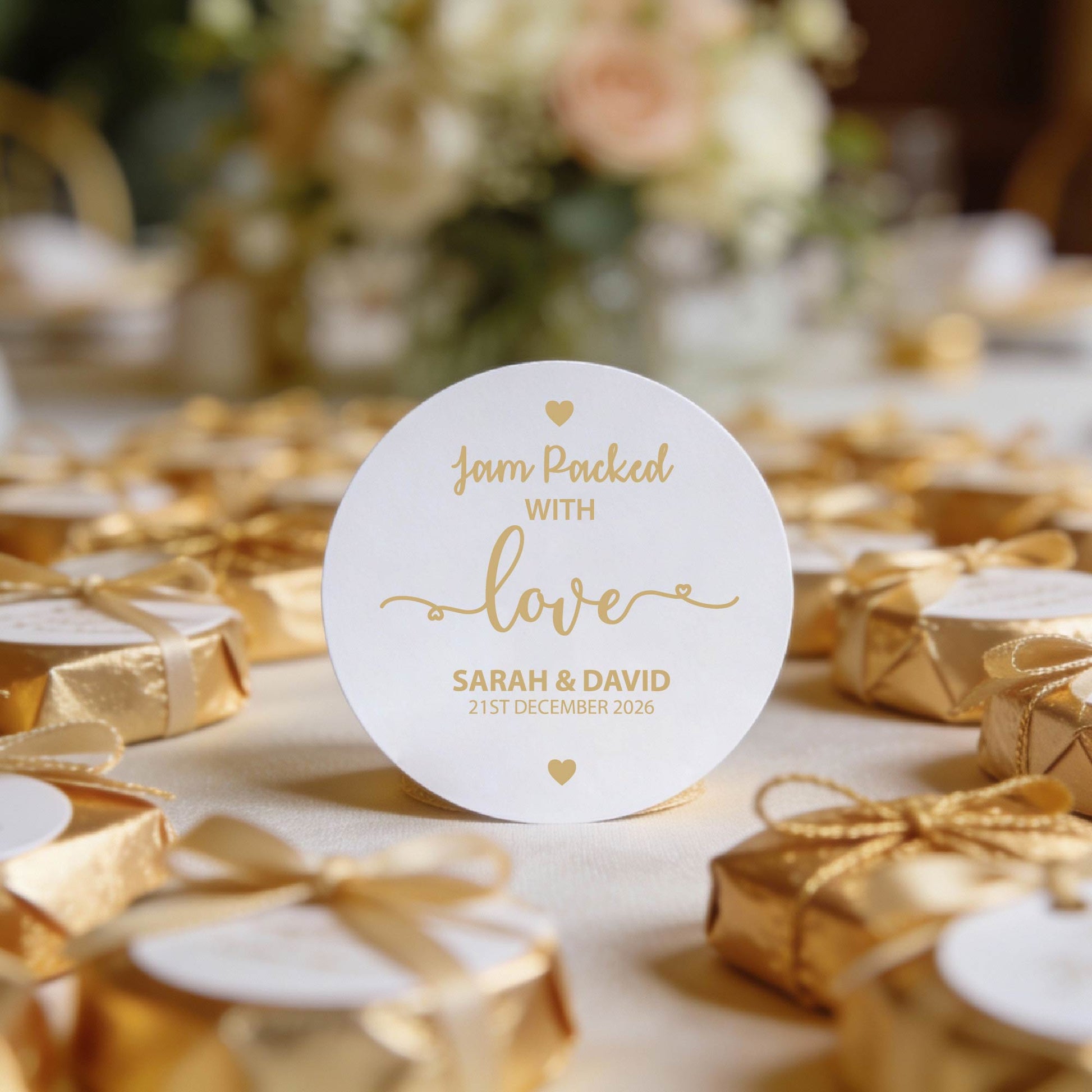 A round, white gloss sticker with gold foil text reads "Jam Packed With Love" and "Sarah & David 21st December 2026"