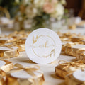 A round, white gloss sticker with the initials 