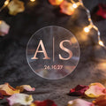 A monogram sticker with initials in the centre separated by a line in the middle and a date at the bottom finished in rose gold foil.