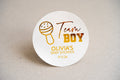 A round white sticker with 'Team BOY' written in gold, and a baby rattle icon, indicating it's for a baby shower. Below there's a personalised text that reads 'OLIVIA'S BABY SHOWER 17.