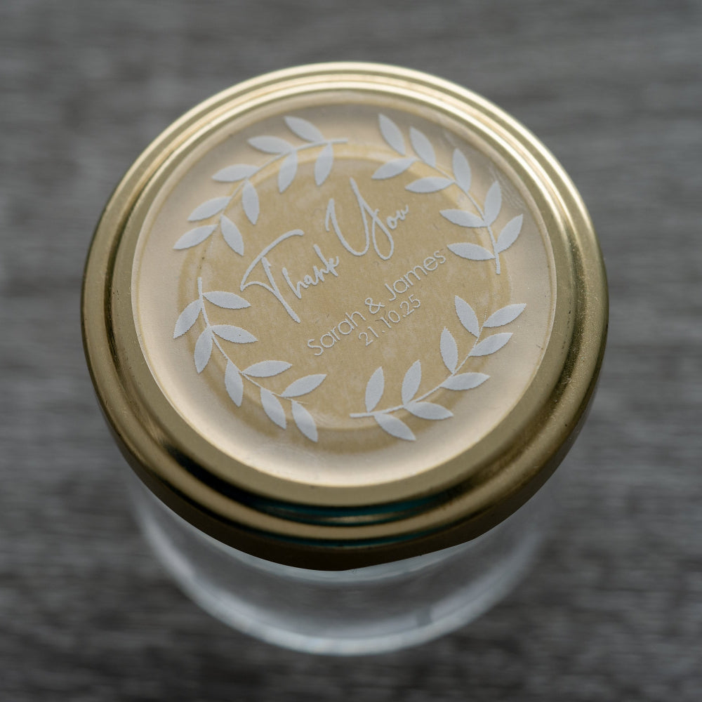A custom round white sticker with a 'Thank You' message, leaf design, and personalised text including names and a date.