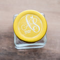 Glass jar with a gold lid featuring a frosted clear sticker printed with white ink 'Amanda & Sam' on a wooden surface