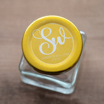 A clear round sticker with a monogrammed design on a glass jar, presenting a personalized and elegant appearance.