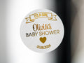 The name of the mummy-to-be in the centre of the sticker using a lovely hand written font. A banner announcing the sex of the baby on the top of the sticker and the date of the baby shower on the bottom. The whole design embossed in metallic foil
