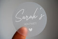 This frosted clear hen party sticker features the bride-to-be's name in elegant white ink using a handwriting font. Perfect for hen party favours, bridal shower décor or gift bags. This personalised sticker adds a unique touch to your celebration.