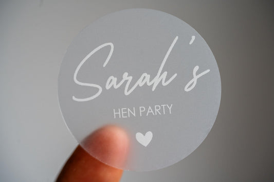 This frosted clear hen party sticker features the bride-to-be&#39;s name in elegant white ink using a handwriting font. Perfect for hen party favours, bridal shower décor or gift bags. This personalised sticker adds a unique touch to your celebration.