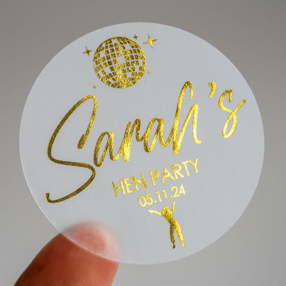 Adorned with a lovely metallic gold foil, the bride-to-be's name is centre in a lovely handwriting font. There is an image of a disco ball and dancing queen at the top and bottom of the sticker to match the party theme of the hen party.