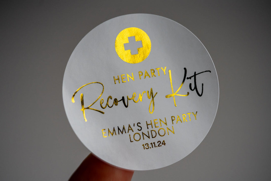 Adorned with a lovely metallic gold foil, "Recovery Kit" written in the centre using a lovely handwriting font. The bride-to-be's name at the bottom with the date of the hen party at the bottom. On the top is the emblem of the red cross in foil.
