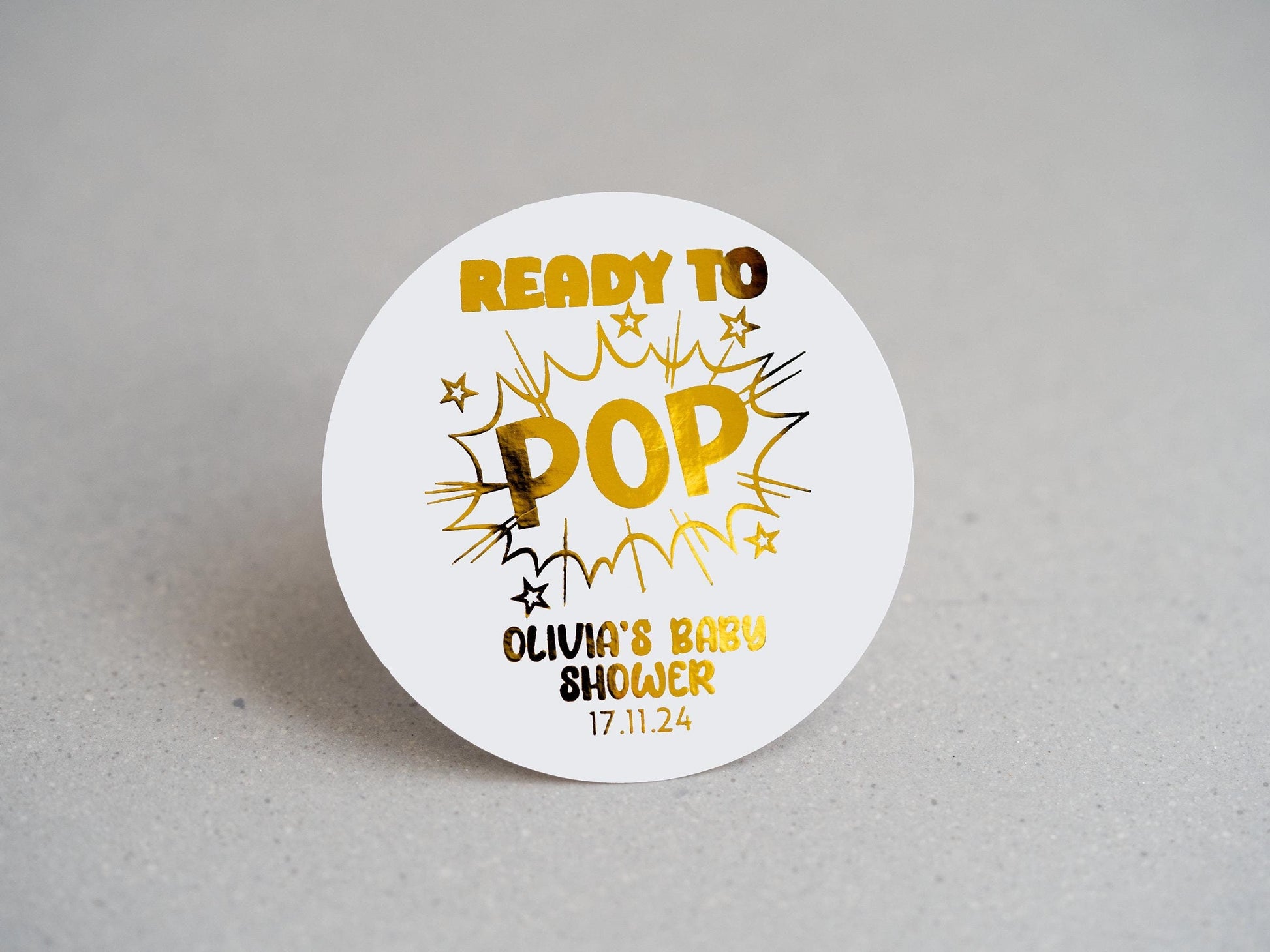 A unique comic book explosion design, featuring &quot;POP&quot; in bold, with &quot;Ready To&quot; above. The mother&#39;s name and shower date are elegantly embossed in gold at the bottom. Ideal for memorable baby shower favours and decorations!