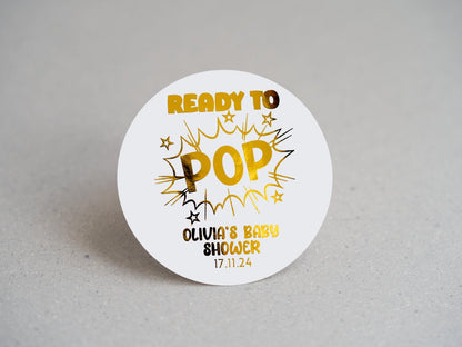 A unique comic book explosion design, featuring &quot;POP&quot; in bold, with &quot;Ready To&quot; above. The mother&#39;s name and shower date are elegantly embossed in gold at the bottom. Ideal for memorable baby shower favours and decorations!