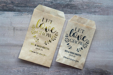 Custom wedding favour for guests to put flower seeds inside. "Let love grow" written on the top with a leaf frame around the words. The name and date of the happy couple sits in the middle and "Plant me & Let Love Grow" written on the bottom.