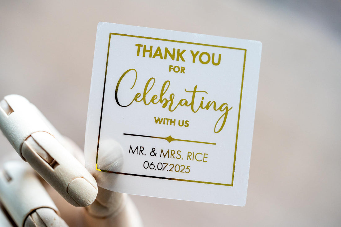 Custom square sticker with "Thank You For Celebrating with Us" written on the middle of the sticker. At the bottom of the sticker is the name of the bride & groom and the date of their special day. The sticker is layered with lovely metallic foil