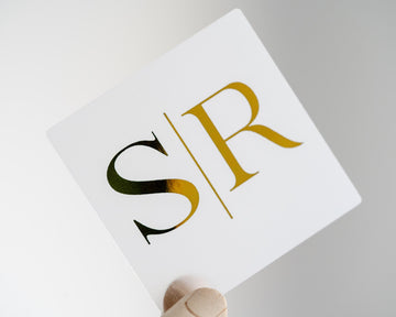 Frosted Clear Sticker with gold foil and initials 'S' and 'R' on a light gray background