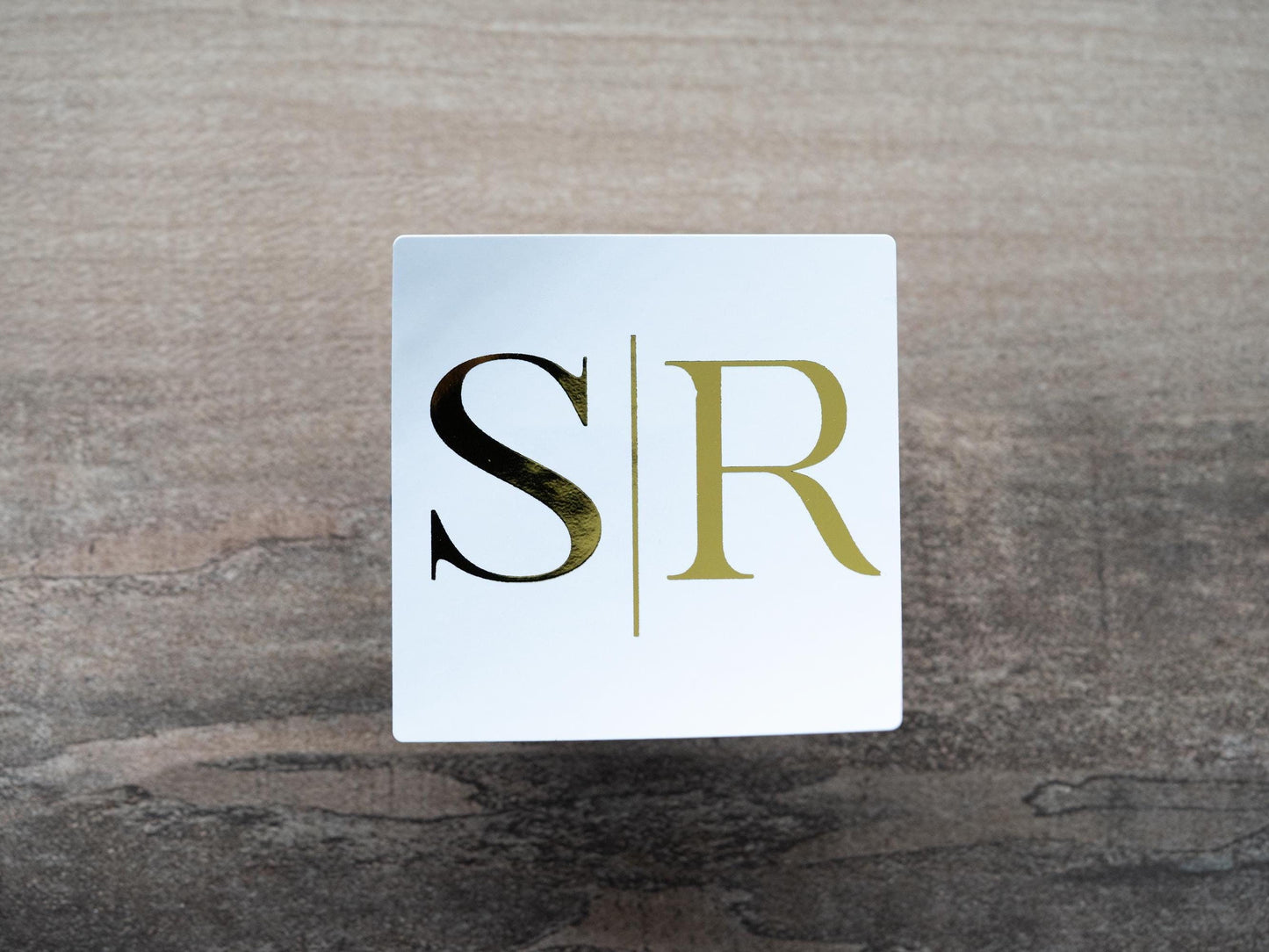 Custom square monogram wedding stickers. The initials are of the happy couple sit in the middle separated with a line in the middle. The design is adorned with a lovely metallic foil for a lovely shine.