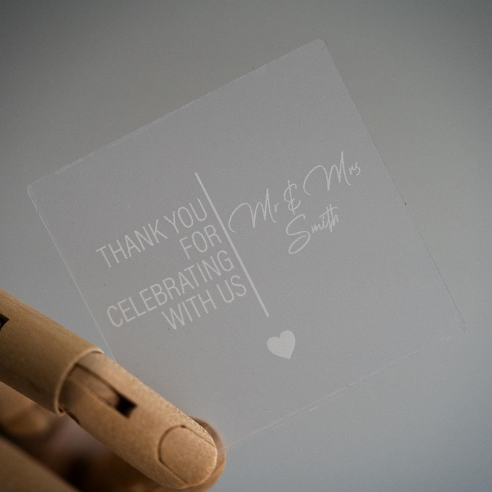 Frosted clear with lovely print with the message "Thank you for celebrating with us" and the name of the happy couple in a lovely curvy font. A line separates the words in the middle and a heart finishes the sticker off. Printed using white ink.