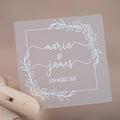Frosted clear square sticker with a leaf square border. The names of the happy couple sit in the middle of the sticker using a lovely handwritten font. The wedding date finishes the sticker, the sticker is printed using a lovely white ink.