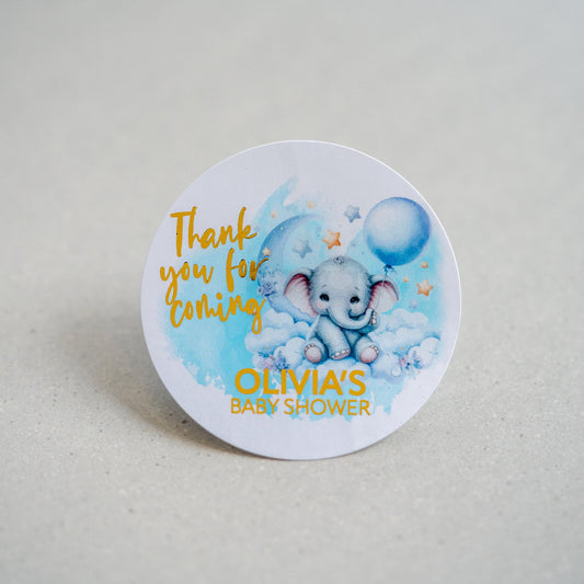 A baby shower sticker with a lovely colour print of an elephant sitting on clouds. We have &quot;Thank you for coming&quot; written in a handwriting font next to the elephant and the mother to be&#39;s name on the bottom. The writing is finished with metallic foil