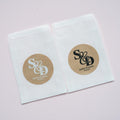 Kraft stickers with the initials of the happy couple in the centre of the stickers. Name and date sits beneath in a choice of white and black ink print. on a white glassine envelope