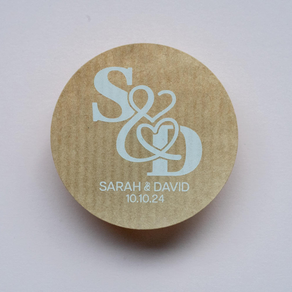 Round kraft sticker with 'S & D' initials and 'Sarah & David 10.10.24' text printed using white ink