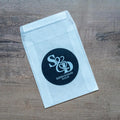A black monogram sticker printed using white ink on a glassine envelope, the initials of the happy couple sit in the middle. The names and wedding date finish the sticker off at the bottom.