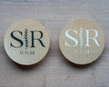 Two kraft stickers with monogram design and date design on a wooden surface