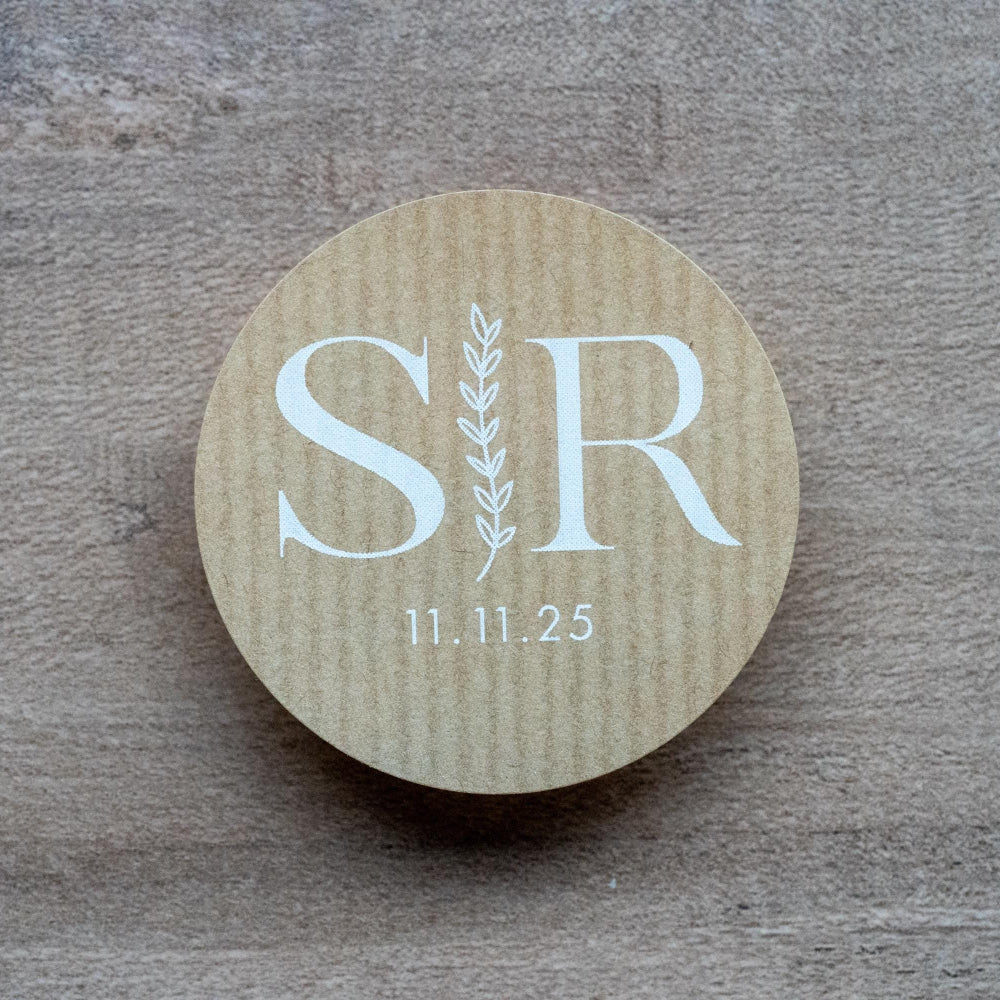 Custom kraft monogram wedding stickers with couple's initials and a leaf branch design.