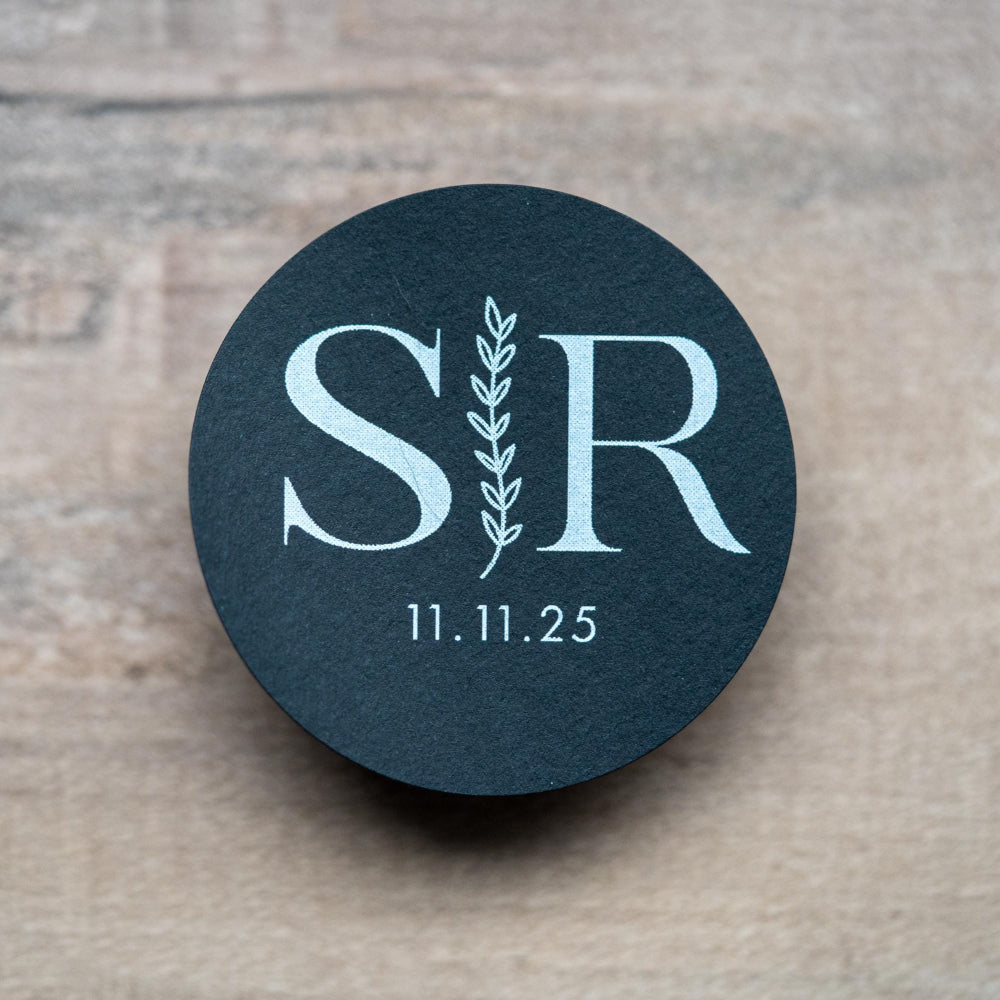 A custom monogram sticker on a black sticker with white print. The initials sit in the centre separated by a leaf line and finished with a date at the bottom.