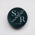 Black circular sticker with 'S R' initials and date on a white background