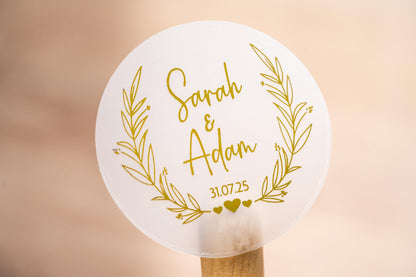 Personalised wedding sticker with the happy couples name in the middle of the sticker using a lovely handwritten font. The date sits under the names and a leaf frame surrounds the name with hearts at the bottom. Gold foil is added for a lovely shine