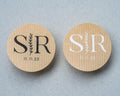 Two kraft stickers with monogram 'SR' and date '11.11.25' on a grey background