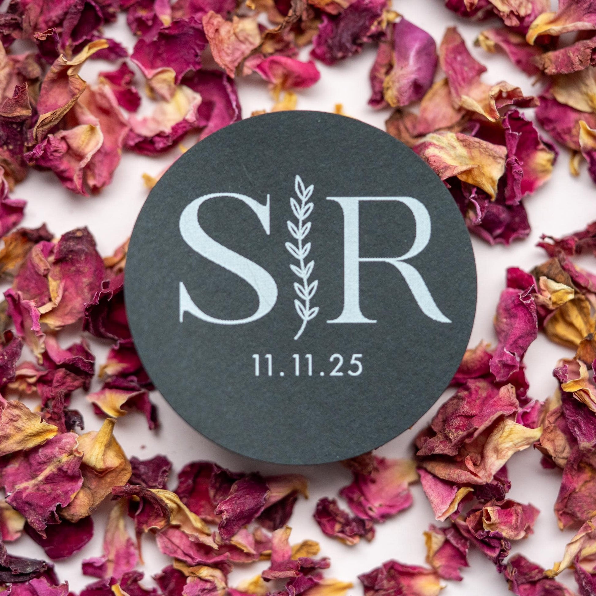 A custom monogram sticker on a black sticker with white print. The initials sit in the centre separated by a leaf line and finished with a date at the bottom.