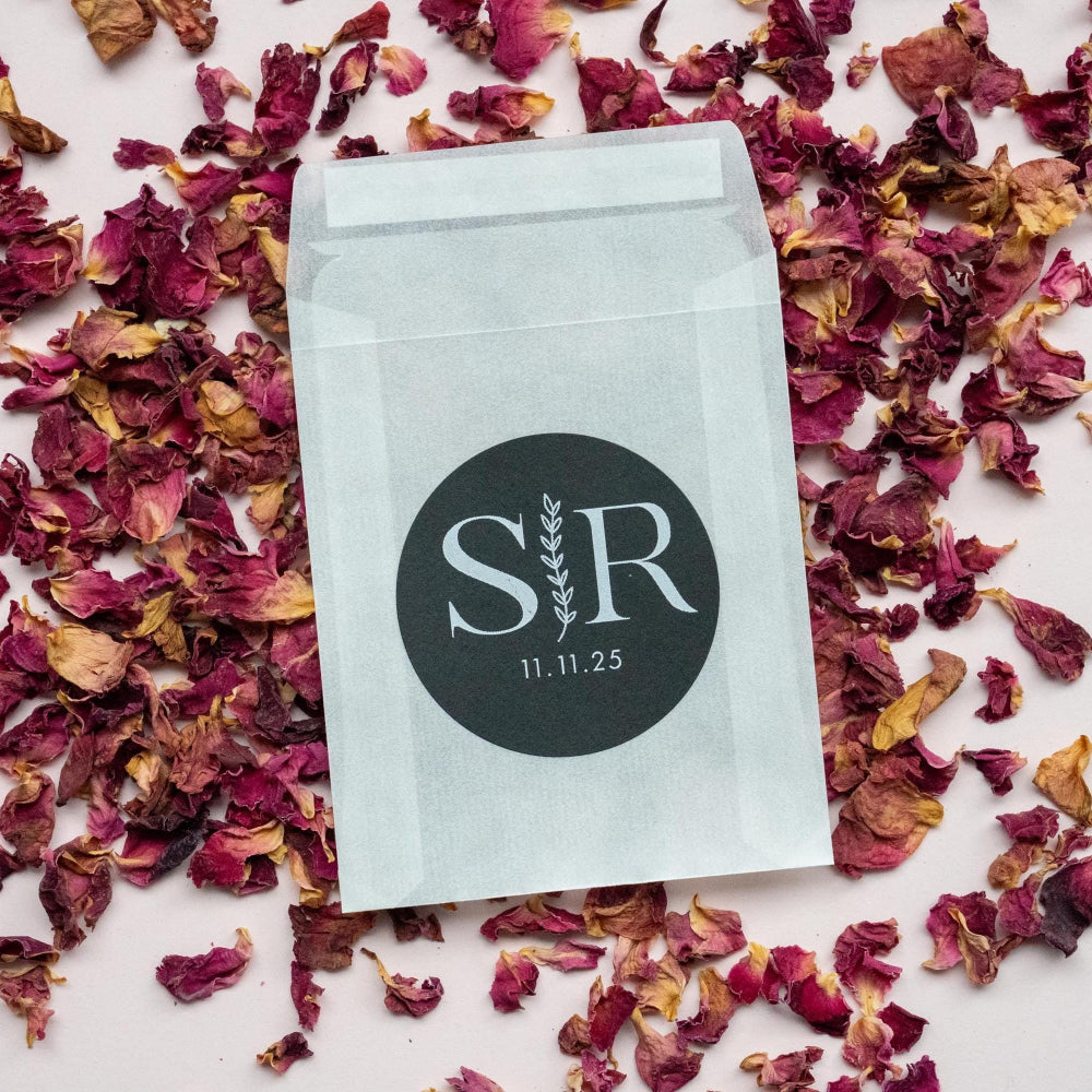 A custom monogram sticker on a black sticker with white print. The initials sit in the centre separated by a leaf line and finished with a date at the bottom.
