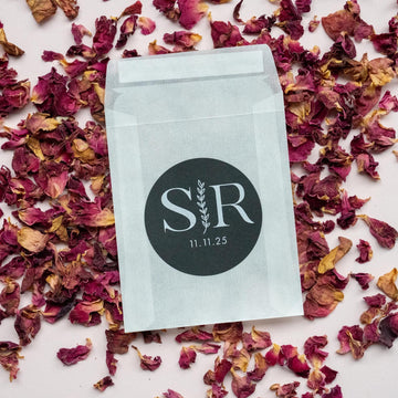 A custom monogram sticker on a black sticker with white print. The initials sit in the centre separated by a leaf line and finished with a date at the bottom.