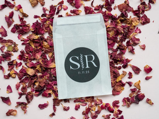 A custom monogram sticker on a black sticker with white print. The initials sit in the centre separated by a leaf line and finished with a date at the bottom.