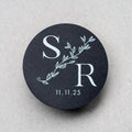 Round black sticker with white monogram and date on a light grey background
