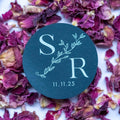 Round black sticker with 'S R' monogram design and date on dried flowers